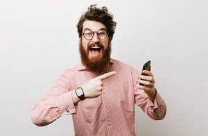 Screaming bearded man with curly-hair and glasses, showing his emotion about new mobile